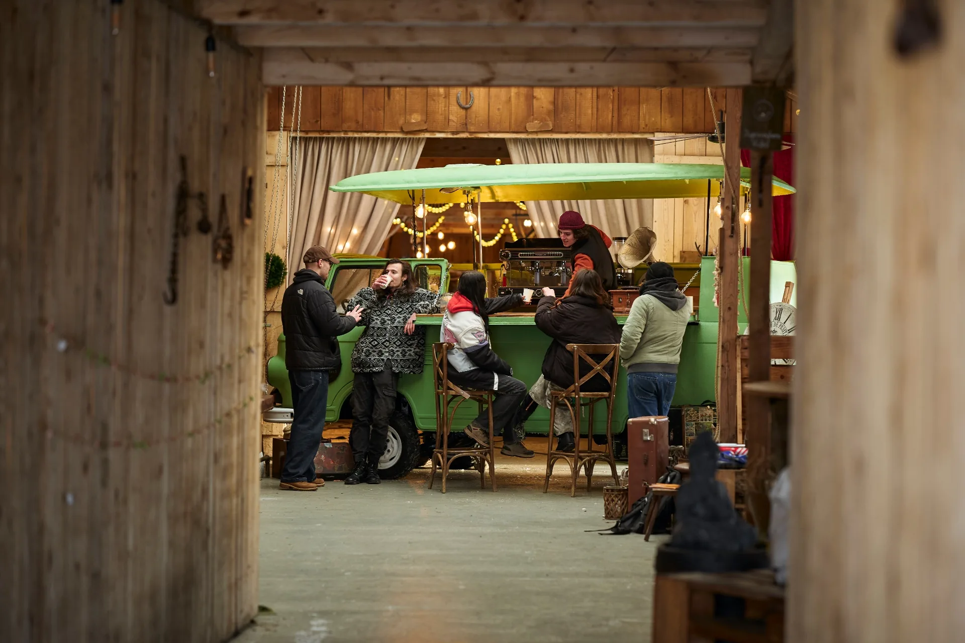 Green van converted into a coffee bar inside a wooden barn