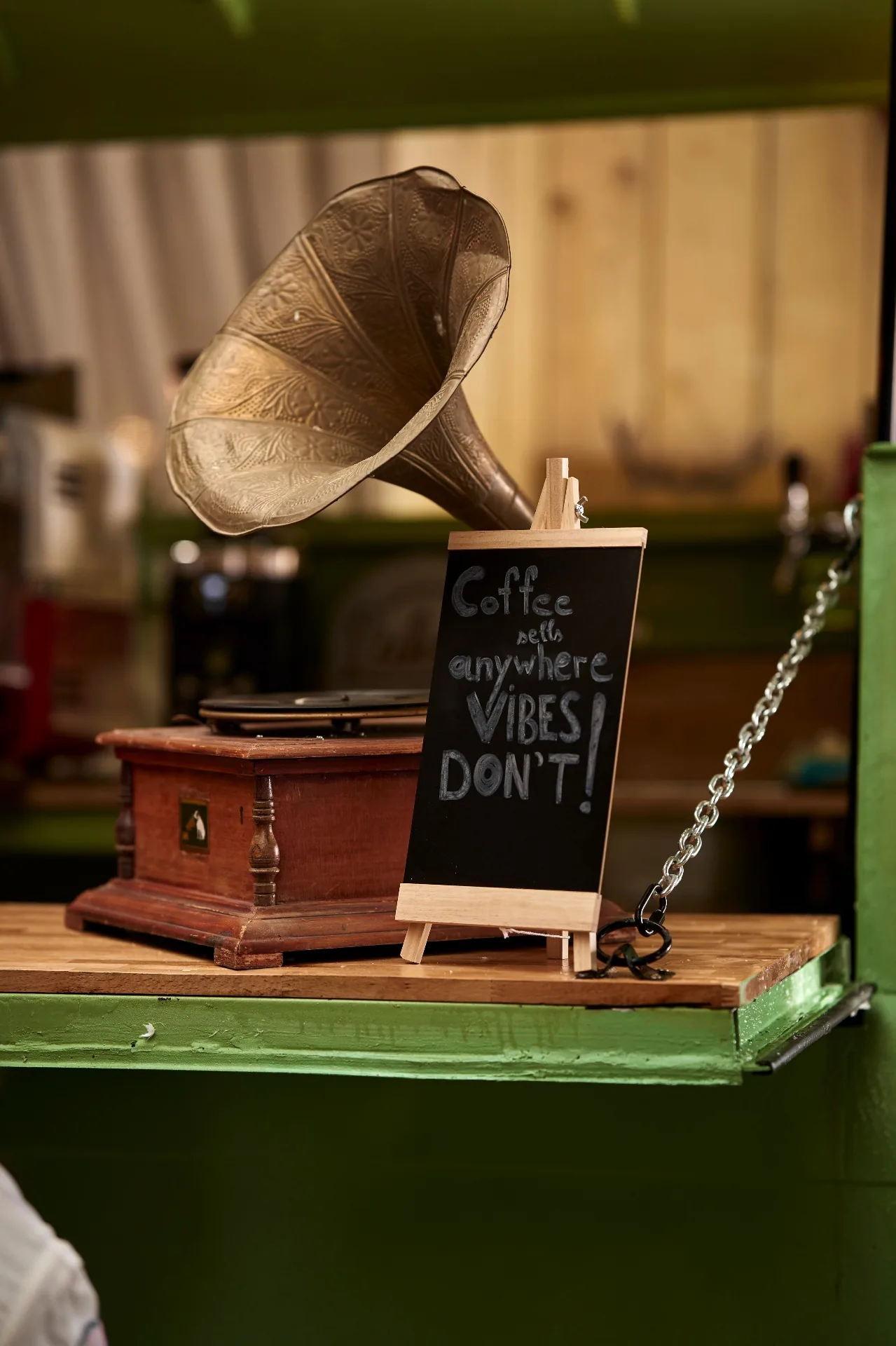 Antique brass gramophone next to chalkboard reading Coffee sells anywhere, vibes don't