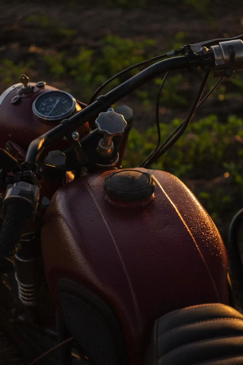 Close-up of a vintage red motorcycle fuel tank and gauge