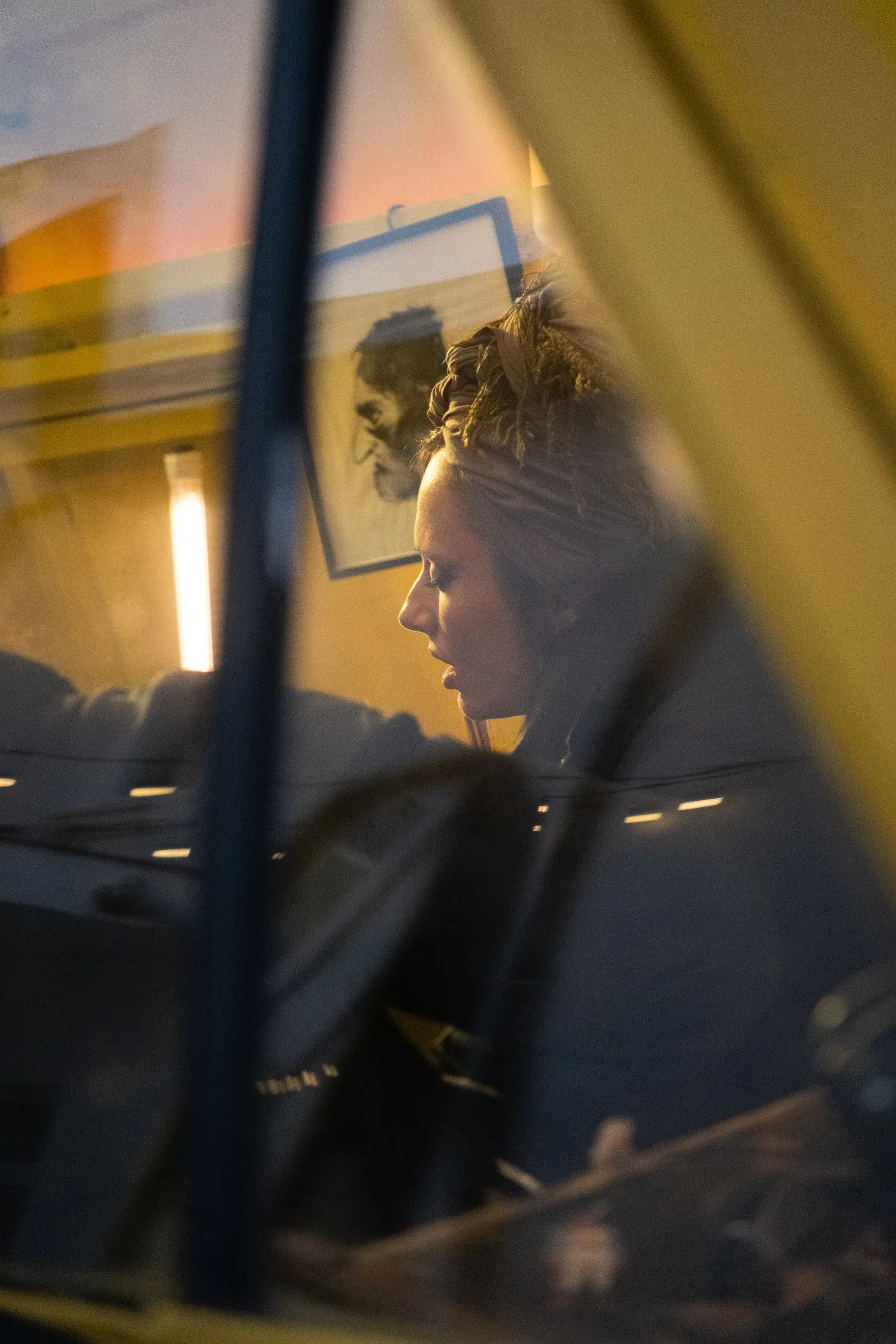 Quiet portrait shot through the yellow van window at dusk